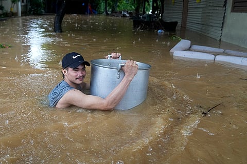Philippines Tropical Storm Yagi: A resident uses a large pot to keep him afloat